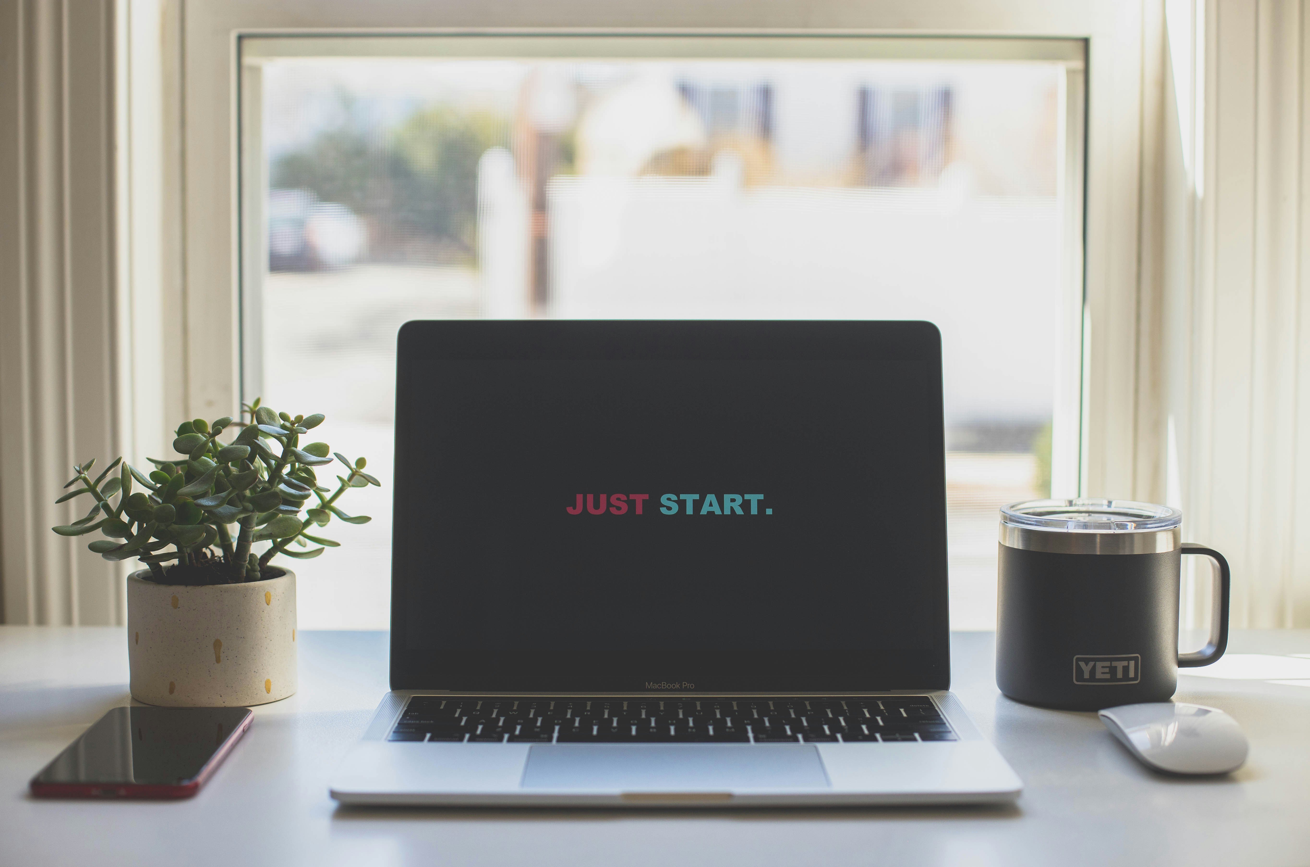 Laptop workspace with motivational Just Start screen, ideal for podcast creators