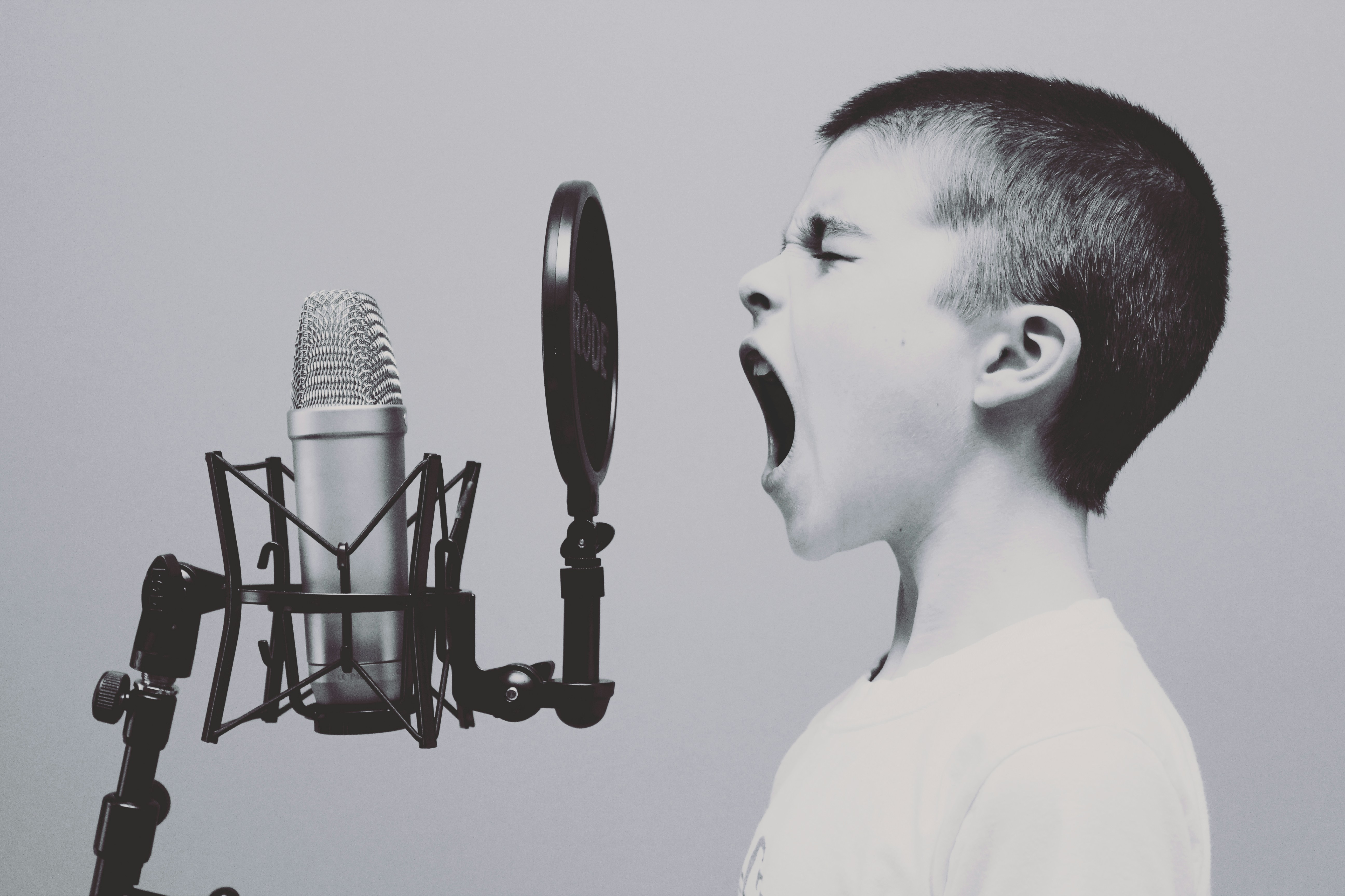 Young boy passionately speaking into a professional microphone, representing expressive podcasting