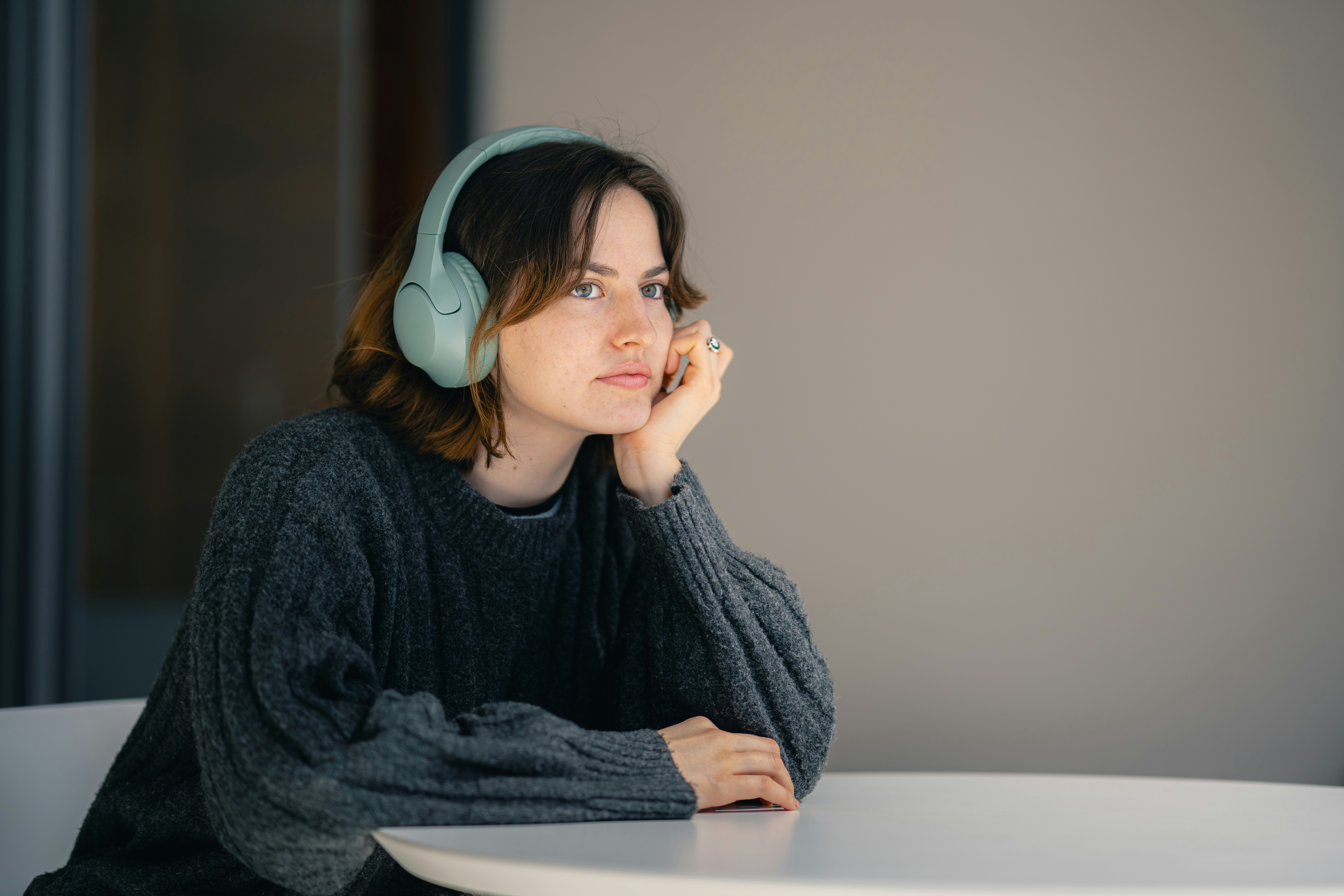 Thoughtful woman wearing headphones, deeply engaged in listening to a podcast