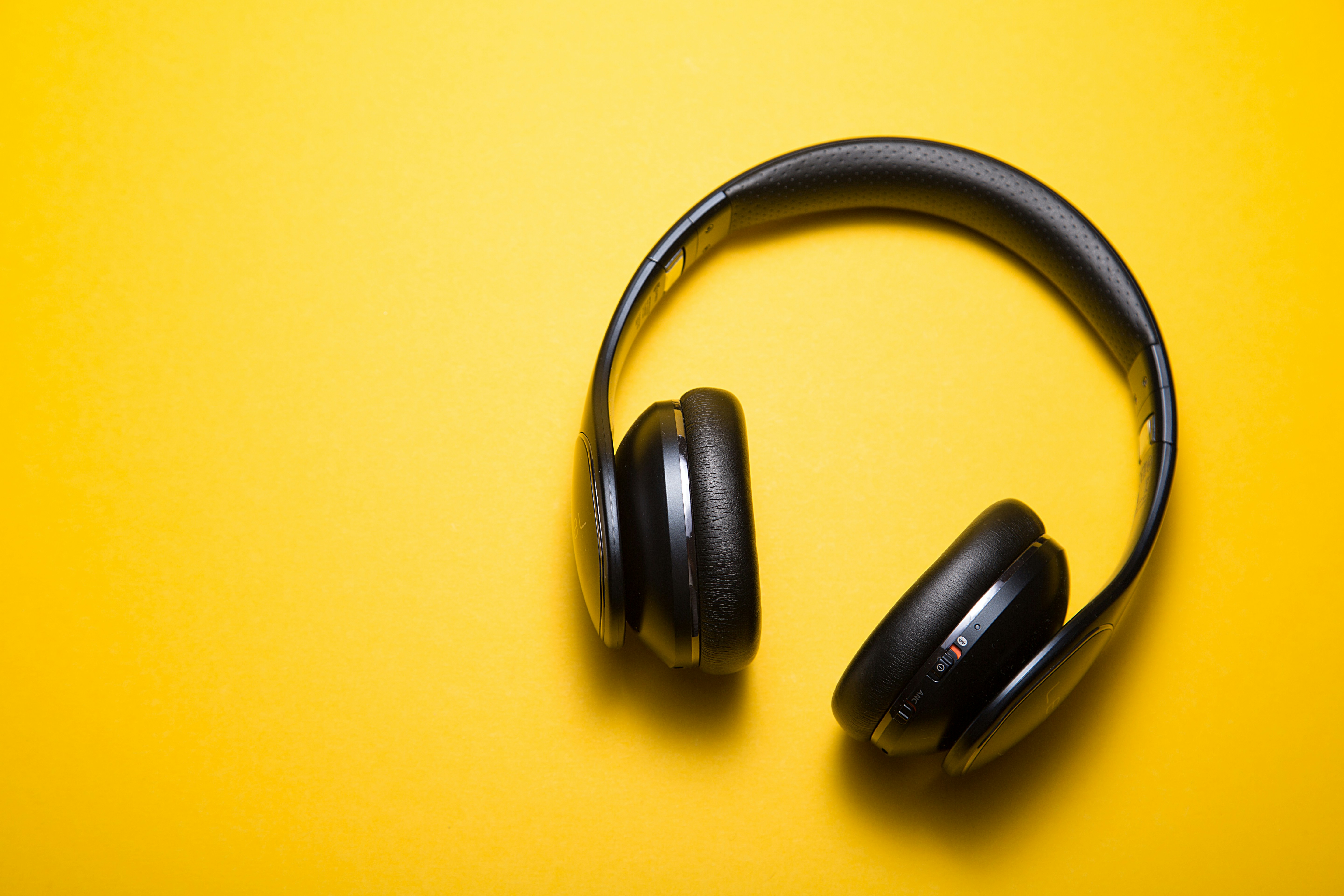 Stylish black headphones isolated on vibrant yellow, perfect for music and podcast listening