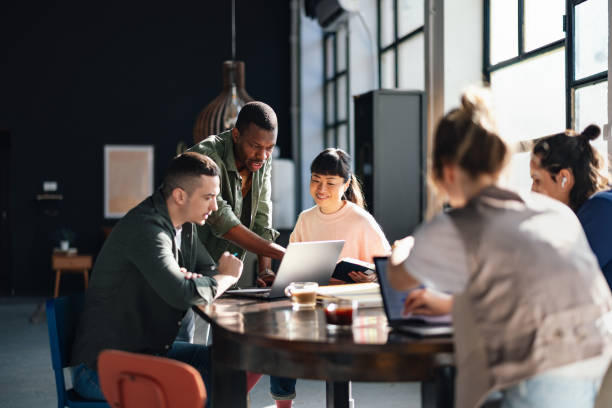 Team collaborating around a laptop in a modern café-style office