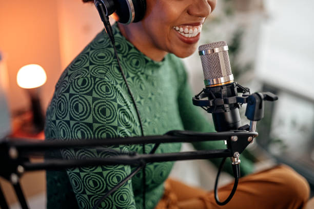Smiling podcaster speaking into a studio microphone during recording