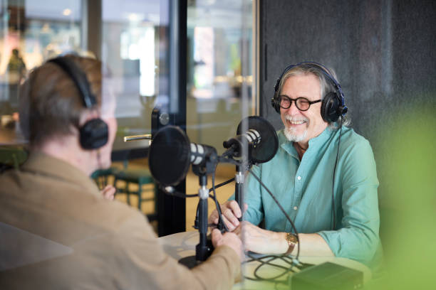 Senior guest and host recording a podcast in a modern office